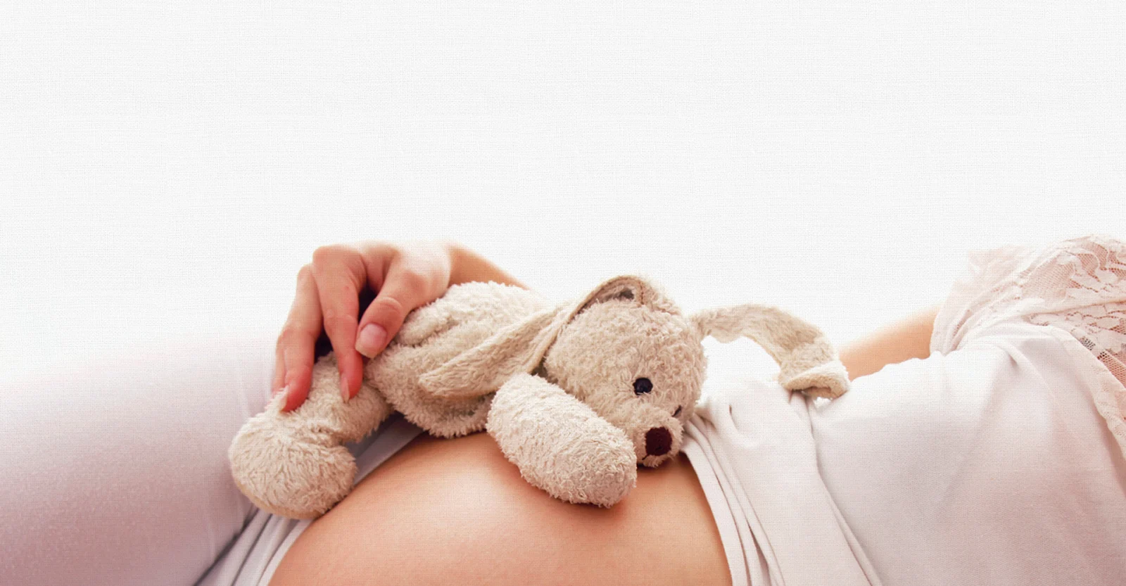 Pregnant woman holding a soft toy on her belly
